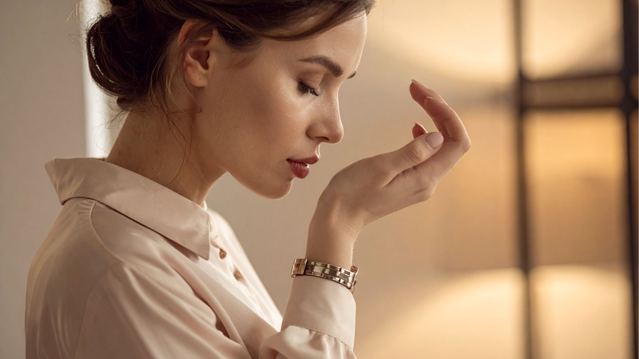 Serene woman in soft pink silk blouse with eyes closed in peaceful contemplation during aromatherapy moment, gentle natural lighting highlighting calm expression